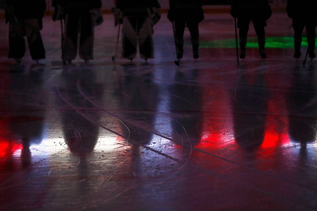The Everett Silvertips stand on the ice during the National Anthem before the season opener against the Vancouver Giants on Saturday, Sep. 24, 2022, at Angel of the Winds Arena in Everett, Washington. (Ryan Berry / The Herald)