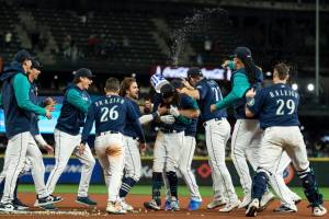 Seattle Mariners, including Adam Frazier (26), J.P. Crawford, center, Chris Flexen (77), Luis Castillo, second from right, and Cal Raleigh, right, celebrate after a single by Crawford in the 11th inning drove in the winning run in a baseball game against the Texas Rangers, Thursday, Sept. 29, 2022, in Seattle. The Mariners won 10-9. (AP Photo/Stephen Brashear)