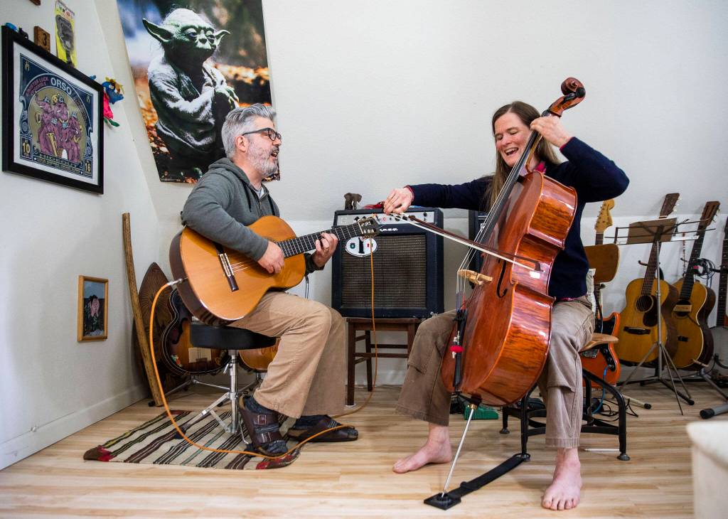 Phil Spirito and his wife, Libby Reed, play a song together in their home in Monroe. (Olivia Vanni / The Herald)