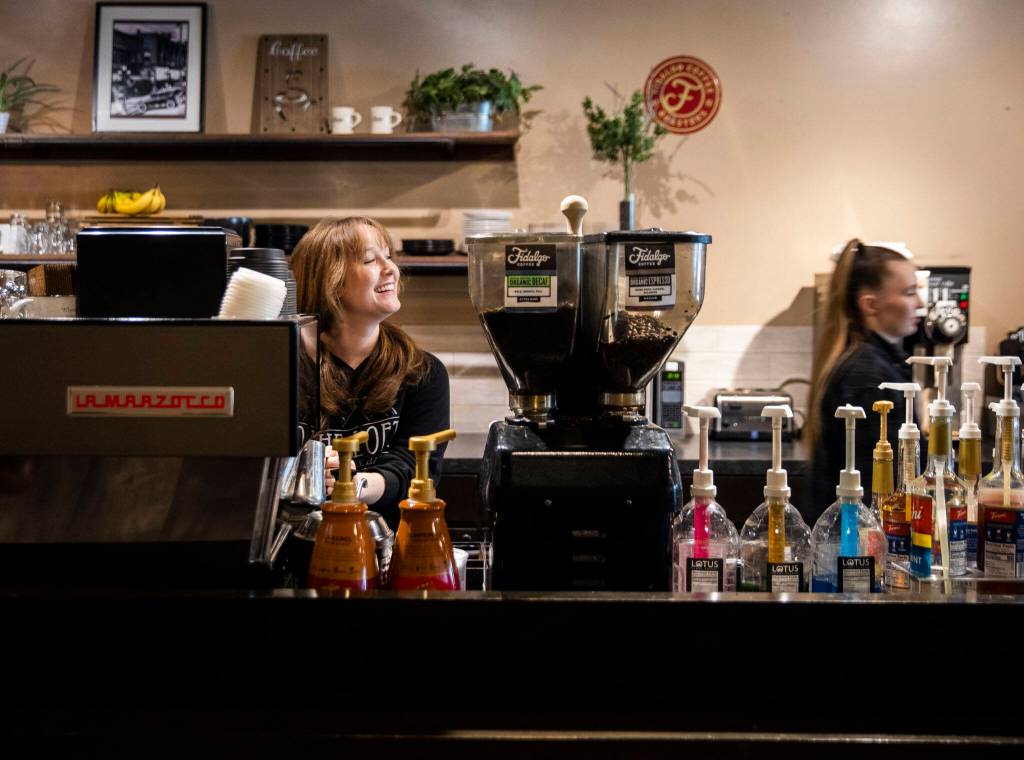 Manager Elyssa Wallgren, left, smiles and greets a customer while making a coffee at The Loft Coffee Bar on Thursday, in Everett. (Olivia Vanni / The Herald)