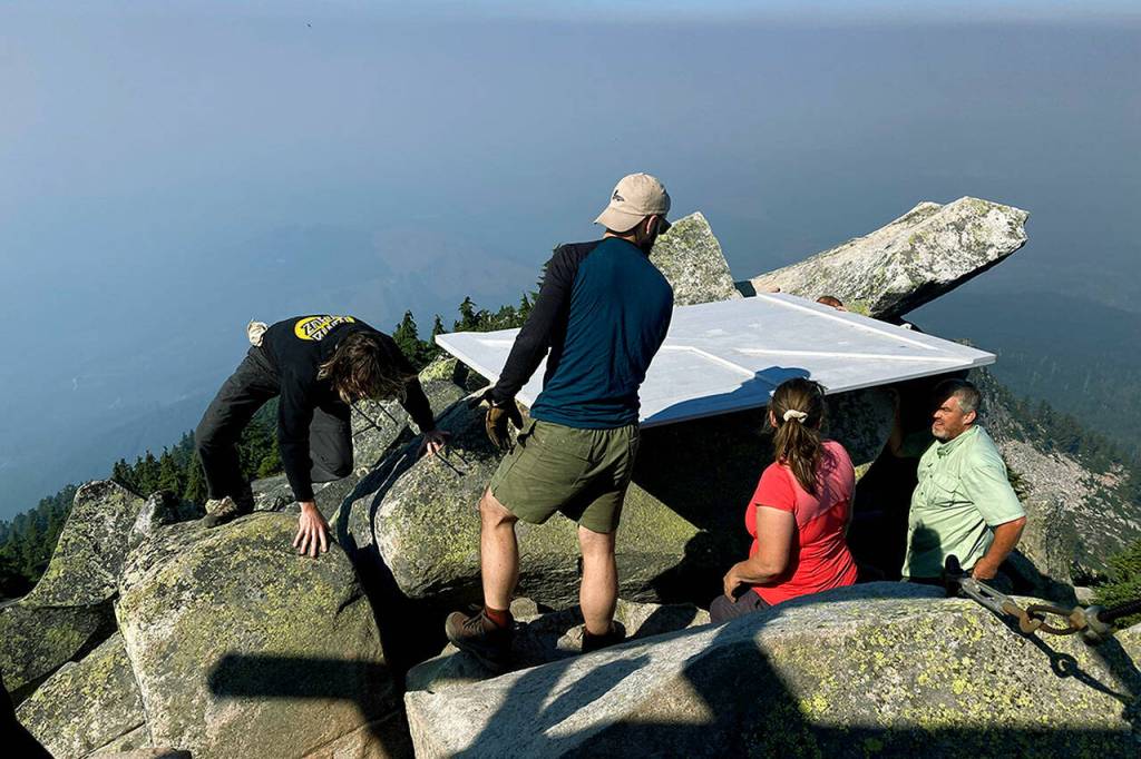 Workers move a window shutter on the mountain summit below the Pilchuck fire lookout on Sept. 9. (Ellen Dennis / The Herald)
