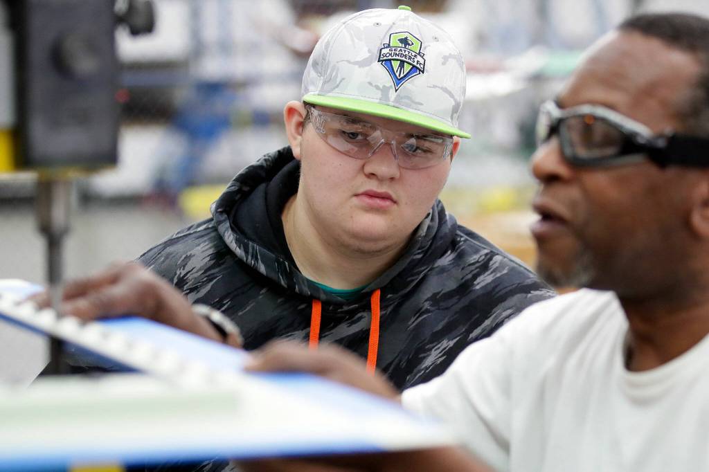 Asher Guillen watches as his mentor, Terry Pierce, rivets plane parts on Sept. 23, at Pathfinder Manufacturing in Everett. (Kevin Clark / The Herald)