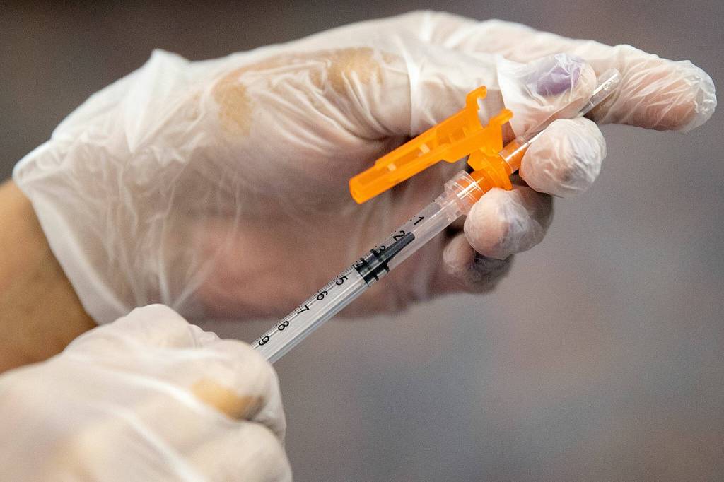 Pharmacist Nisha Mathew prepares a Pfizer COVID booster shot Saturday for a patient at Bartell Drugs on Broadway in Everett. (Ryan Berry / The Herald)