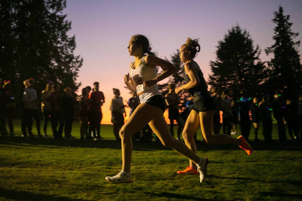 Runners in the Girls 3A-4A 5K approach the two-mile mark during the Nike Twilight Cross Country Invitational on Saturday, Oct. 1, 2022, at Cedarcrest Golf Course in Marysville, Washington. (Ryan Berry / The Herald)