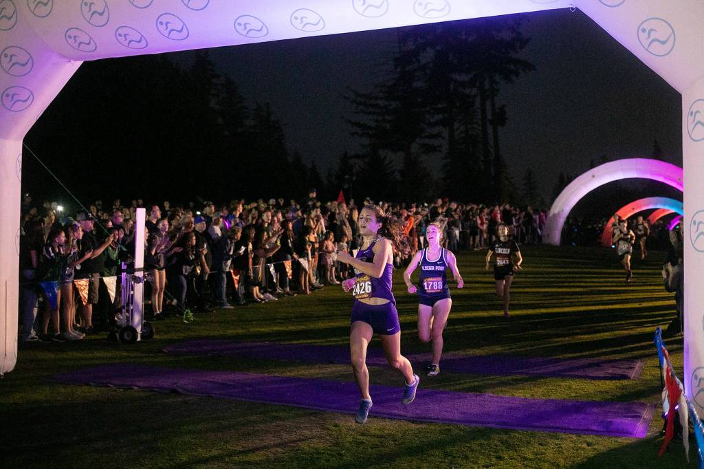 Runners in the Girls 3A-4A 5K cross the finish line during the Nike Twilight Cross Country Invitational on Saturday, Oct. 1, 2022, at Cedarcrest Golf Course in Marysville, Washington. (Ryan Berry / The Herald)