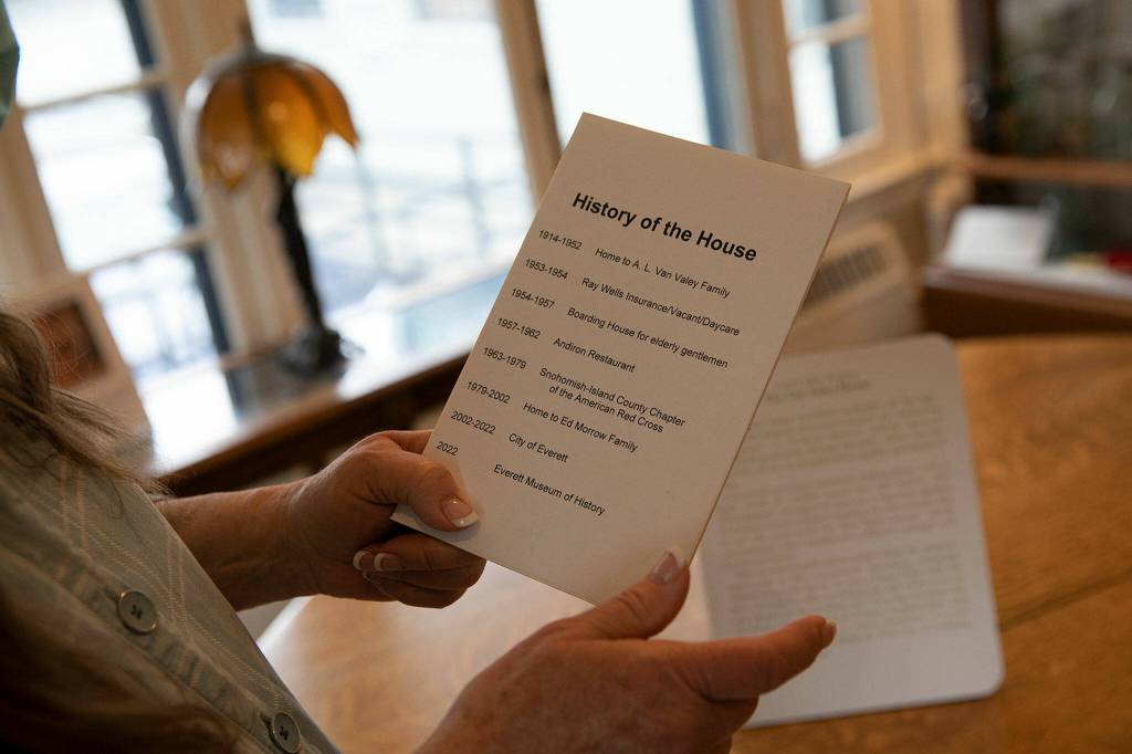 Everett Museum of History executive director Barb George on Tuesday holds a card that offers a brief list of the Van Valey Houses many uses over its history. (Ryan Berry / The Herald)