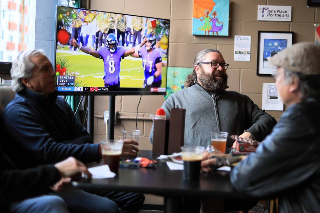 Jay Nordquist, left, to right, Todd Pullman and Deek Slovek share a table on Dec. 24, 2021, at Brews Almighty, in Everett. (Kevin Clark / The Herald)