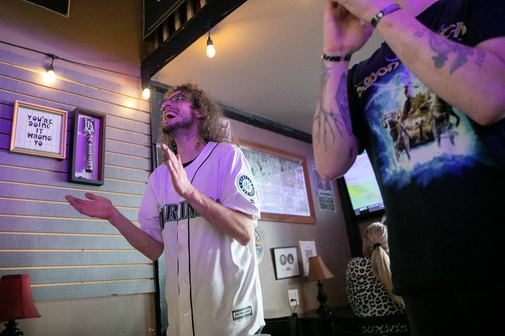 Aaron Britton, 33, left, and little brother Jonathan Britton, 32, stand and clap as the final out unfolds during Game 1 of the Mariners Wildcard matchup with the Toronto Blue Jays on Friday, at Brews Almighty® in Everett. (Ryan Berry / The Herald)