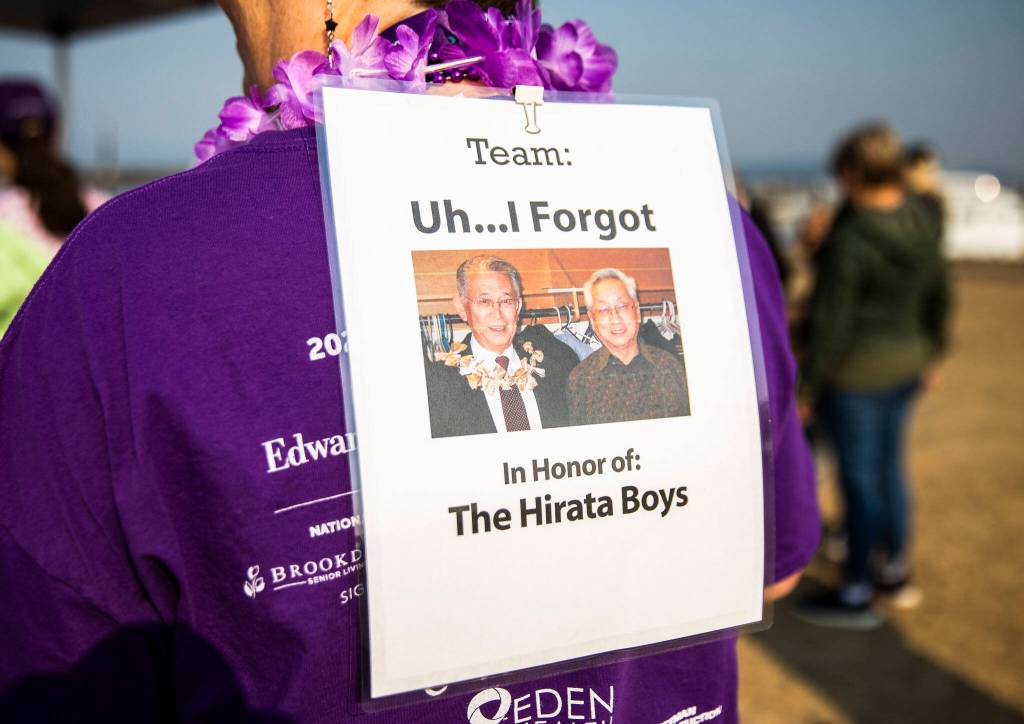 A family walks with signs remembering their family members with alzheimers that have passed during the annual Walk to End Alzheimers on Saturday at Boxcar Park in Everett. (Olivia Vanni / The Herald)