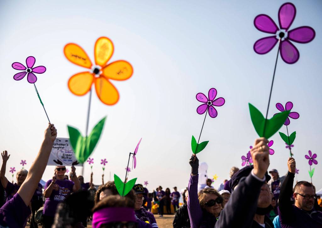 People hold up their flowers during the Promise Garden ceremony during the annual Walk to End Alzheimers on Saturday at Boxcar Park in Everett. (Olivia Vanni / The Herald)
