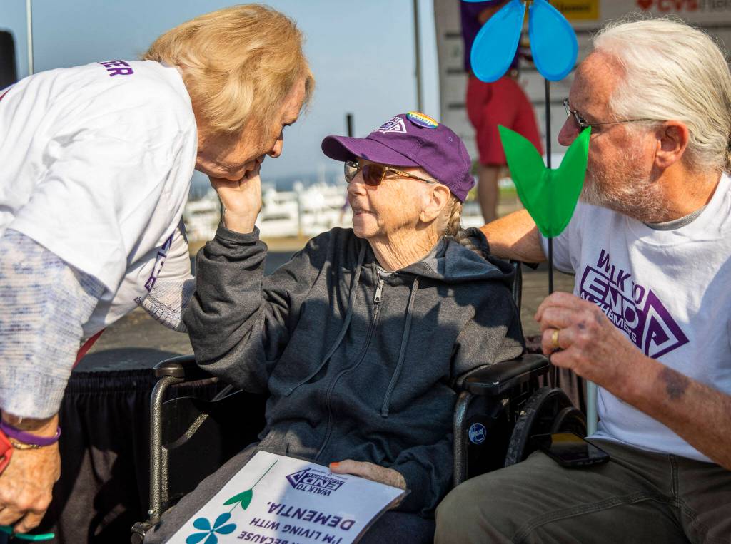 Jenny Duffey, center, touches the face of Katie Rielinger, her friend of more than 20 years, during the annual Walk to End Alzheimers on Saturday at Boxcar Park in Everett. (Olivia Vanni / The Herald)