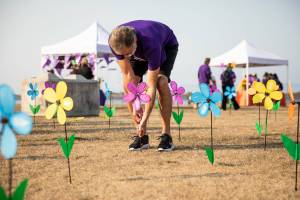 Rob Arbuckle puts a flower in the ground to remember his father Bob during the annual Walk to End Alzheimers at Boxcar Park on Saturday, Oct. 8, 2022 in Everett, Washington. (Olivia Vanni / The Herald)