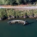 A derelict boat half underwater along the bank of Ebey Slough on Tuesday, in Everett. (Olivia Vanni / The Herald)