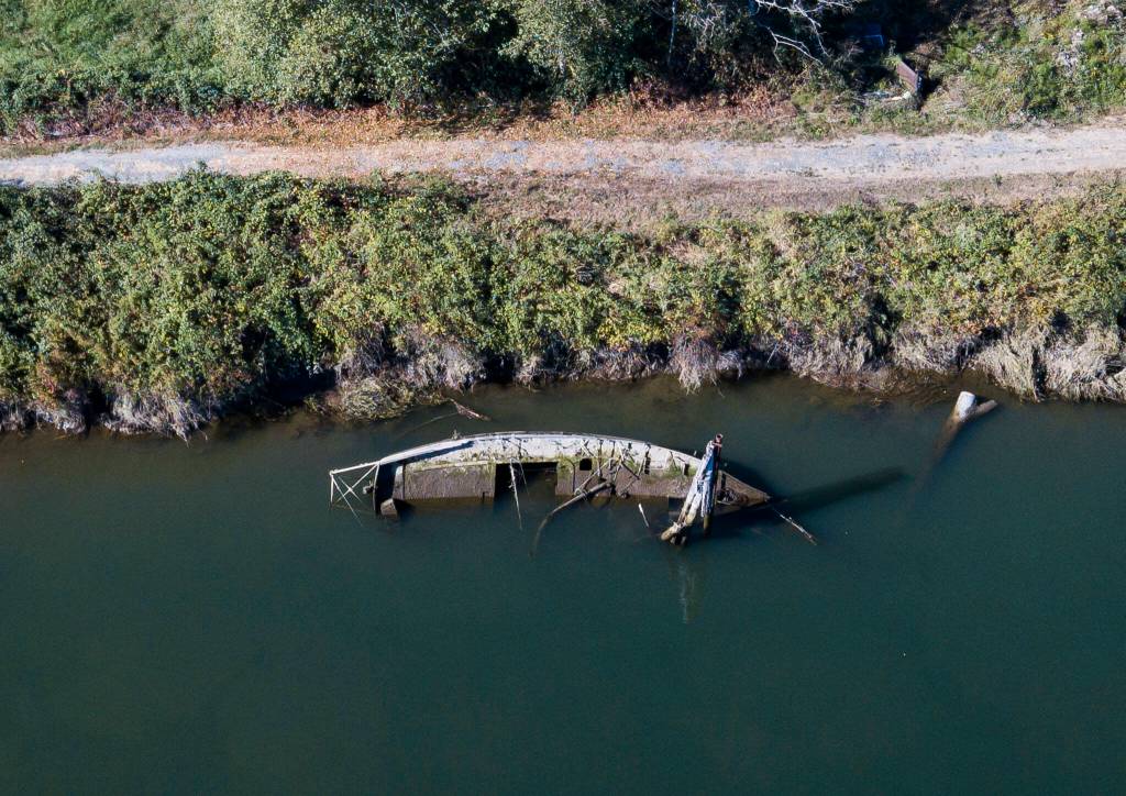 A derelict boat half underwater along the bank of Ebey Slough on Tuesday, in Everett. (Olivia Vanni / The Herald)