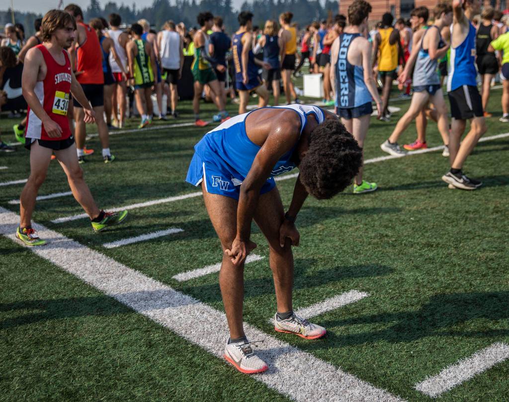 A runner bends over to catch their breath after finishing their race at the Hole In The Wall Invitational on Saturday, Oct. 8, 2022 in Arlington, Washington. (Olivia Vanni / The Herald)
