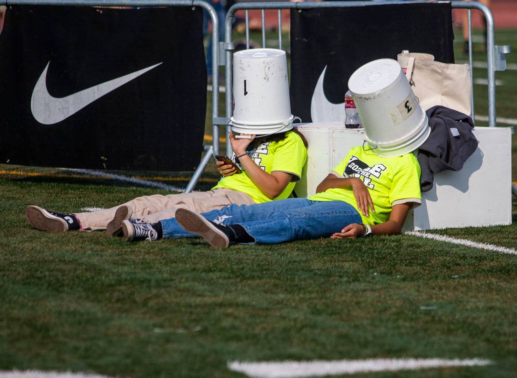 Volunteers wait under buckets between races at the Hole In The Wall Invitational on Saturday, Oct. 8, 2022 in Arlington, Washington. (Olivia Vanni / The Herald)