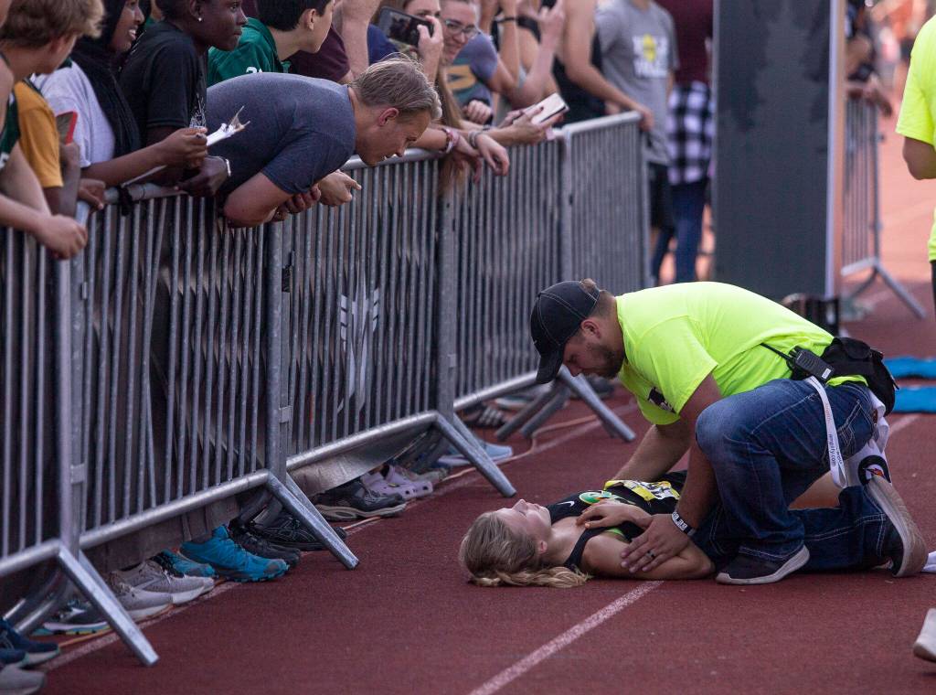 A Roosevelt runner is helped by staff after collapsing at the finish line at the Hole In The Wall Invitational on Saturday, Oct. 8, 2022 in Arlington, Washington. (Olivia Vanni / The Herald)