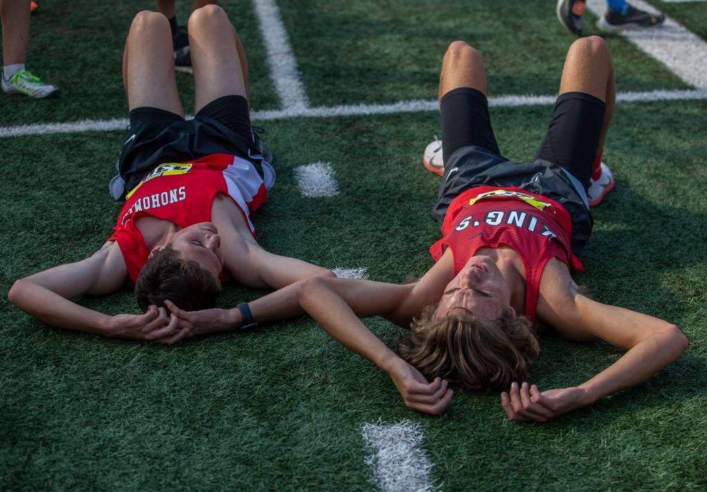 A Snohomish and Kings runner lay on the ground after their race at the Hole In The Wall Invitational on Saturday, Oct. 8, 2022 in Arlington, Washington. (Olivia Vanni / The Herald)