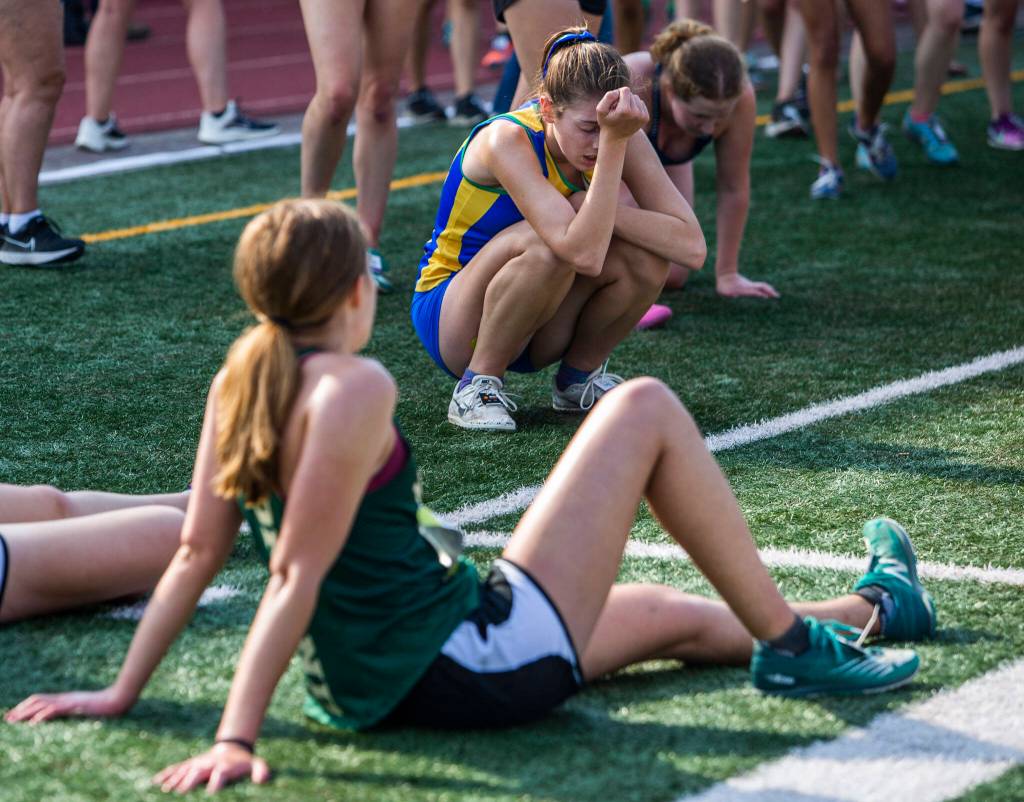 Runners falls and lie on the turf after finishing their race at the Hole In The Wall Invitational on Saturday, Oct. 8, 2022 in Arlington, Washington. (Olivia Vanni / The Herald)