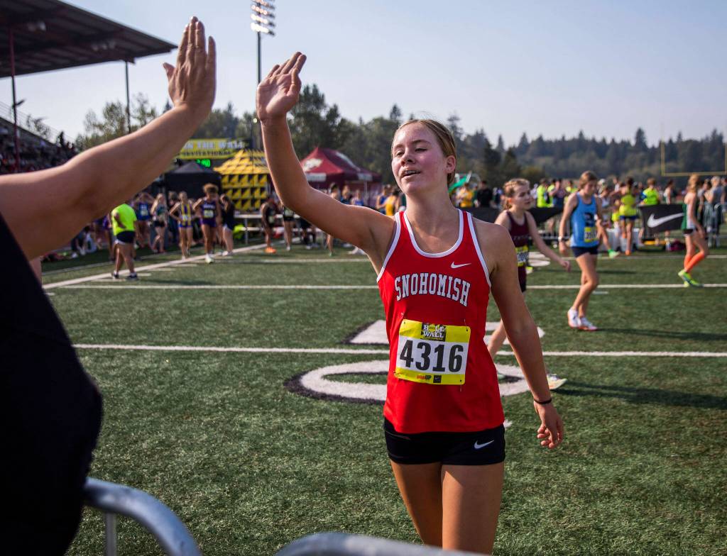 A Snohomish runner high fives a friend after finishing her race at the Hole In The Wall Invitational on Saturday, Oct. 8, 2022 in Arlington, Washington. (Olivia Vanni / The Herald)