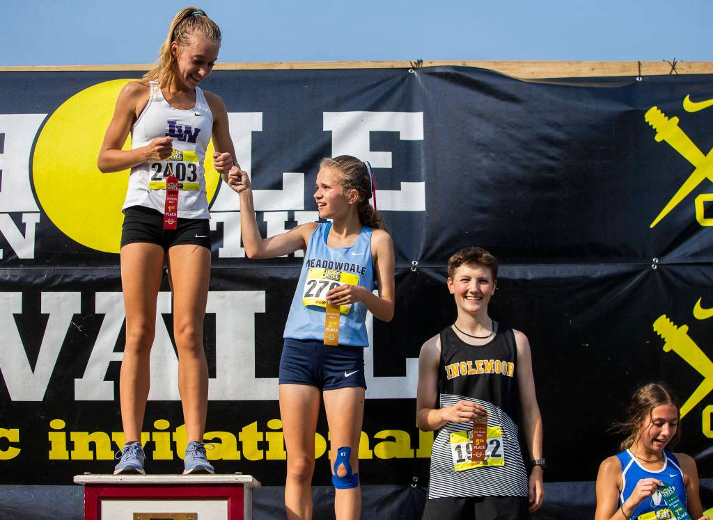 Meadowdale junior Payton Conover fist-bumps girls silver race champion Alexa Matora of Lake Washington. (Olivia Vanni / The Herald)