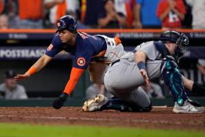 Houston Astros' Jeremy Pena, left, scores past Seattle Mariners catcher Cal Raleigh, right, during the eighth inning on a hit by teammate Alex Bregman in Game 2 of an American League Division Series baseball game in Houston, Thursday, Oct. 13, 2022. (AP Photo/David J. Phillip)