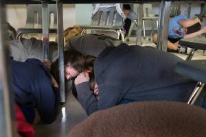 Eve Barrows (left) and the students duck and cover under desks during an Earthquake Drill at Port Susan Middle School on Thursday, Oct. 21, 2021 in Stanwood, Washington.  (Andy Bronson / The Herald)