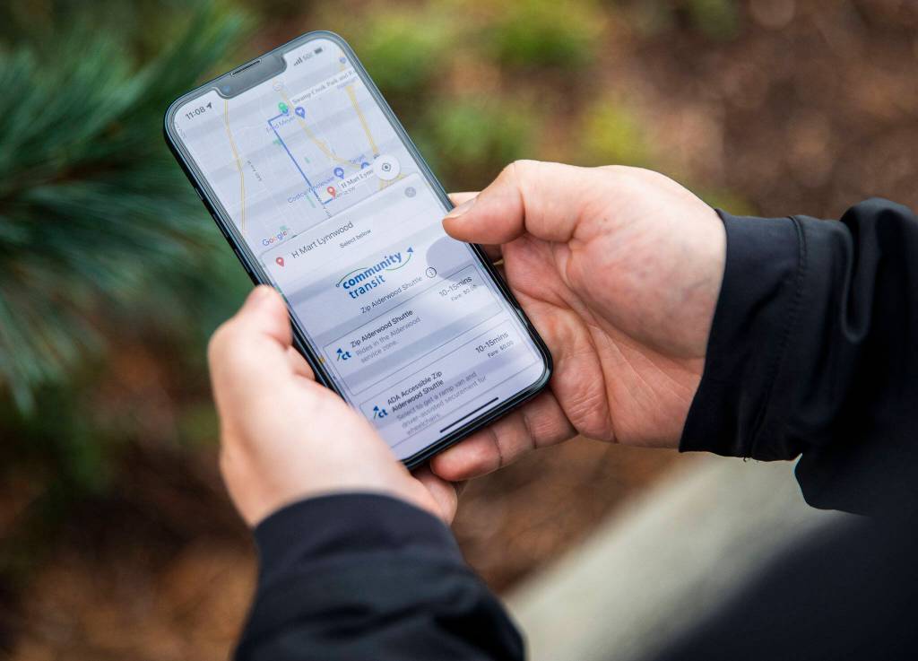 Street Smarts columnist Ben Watanabe uses the Goin  Rides for All app to request a Community Transit Zip shuttle Sunday in Lynnwood. (Olivia Vanni / The Herald)