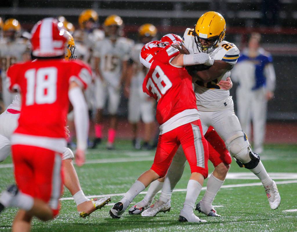 Ferndales Isaiah Carlson drags a pair of defenders for extra yards on a carry against Stanwood Friday, Oct. 21, 2022, at Stanwood High School in Stanwood, Washington. (Ryan Berry / The Herald)