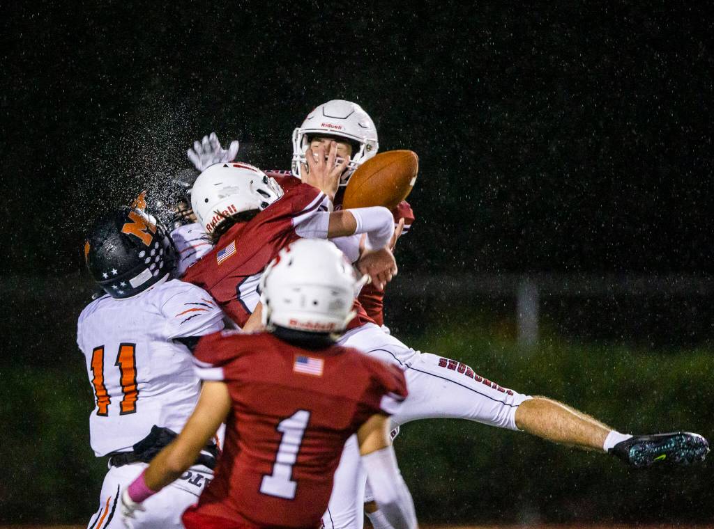 Water sprays as multiple player leap in the air for the ball during a game on Friday, Oct. 21, 2022 in Snohomish, Washington. (Olivia Vanni / The Herald)