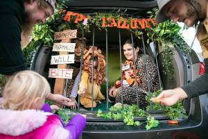 A trick-or-treater gets candy from the Brandon family — Nick, Hope, Emma, Zoey and Kai — who decorated their car as a zoo exhibit for Madison Elementary School's Trunk-or-Treat event on Friday, Oct. 28, 2022, in Everett, Washington. Hundreds of students and family members came out to the school Friday night to show off their costumes and collect candy from over a dozen themed vehicles. (Ryan Berry / The Herald)