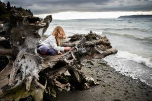 Jane M., plays on a large piece of driftwood while the wind blows her hair and large waves crash into the shore along Mukilteo Beach on Thursday, Oct. 27, 2022 in Mukilteo, Washington. (Olivia Vanni / The Herald)