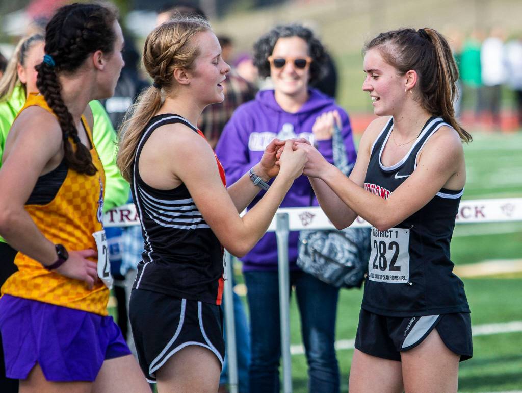 Snohomishs Paige Gerrard, right, fist bumps Monroes Alexis Canovali-McKenzie who finished fourth during the 3A Girls District Cross Country championship race on Saturday, Oct. 29, 2022 in Arlington, Washington. (Olivia Vanni / The Herald)