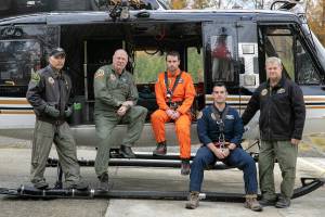 Members of the search and rescue team who extracted hiker Benedict Delahunty from the Enchantments after he became trapped under a boulder in October sit outside their helicopter Wednesday, Nov. 2, 2022, at Taylor’s Landing in Snohomish, Washington. The team includes, from left, chief pilot Bill Quistorf, crew chief Randy Fay, rescue technician Ryan Fleming, flight medic Jeff Brown and pilot Steve Klett. (Ryan Berry / The Herald)