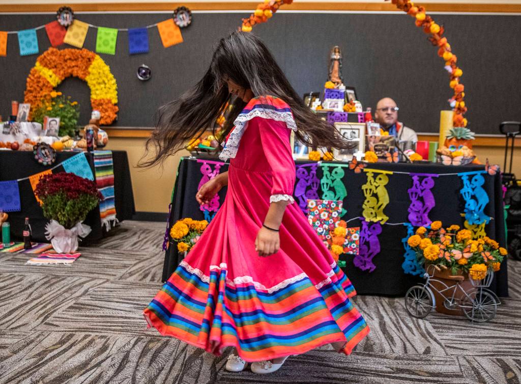Belinda Reyes-Ordoñez, 7, spins in her dress while looking at the different ofrendas at the Washington-Guerrero Foundations Día de los Muertos event at the Lynnwood Convention Center on Saturday, in Lynnwood. (Olivia Vanni / The Herald)