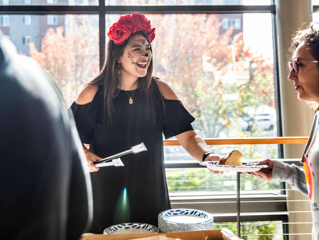Daniela Altamirano-Crosby smiles while serving Pan de Muertos at the Washington-Guerrero Foundations Día de los Muertos event at the Lynnwood Convention Center on Saturday, in Lynnwood. (Olivia Vanni / The Herald)