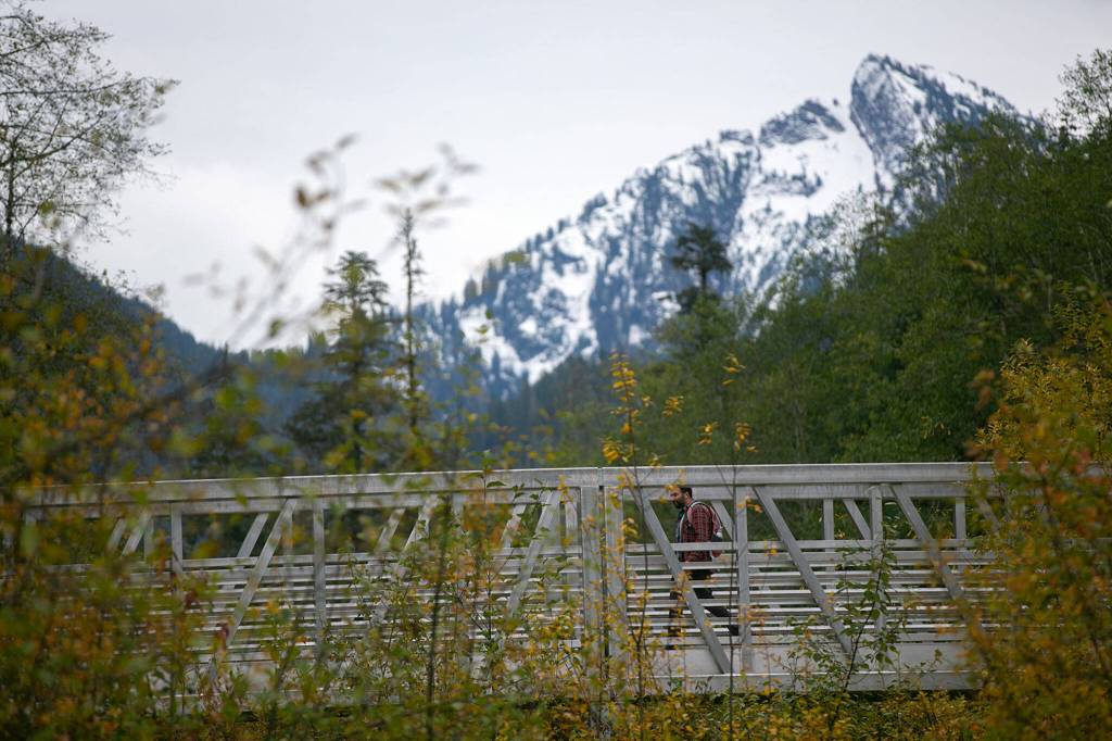 A hiker crosses the South Fork of the Stillaguamish River while heading back to the parking lot on the Big Four Mountain Trail on Oct. 28, in Mount Baker-Snoqualmie National Forest near Granite Falls. (Ryan Berry / The Herald)