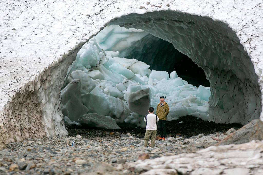 A hiker stands in front of cave-in debris to get his photo taken at one of the ice caves along Big Four Mountain Trail on Oct. 28, in Mount Baker-Snoqualmie National Forest near Granite Falls. (Ryan Berry / The Herald)