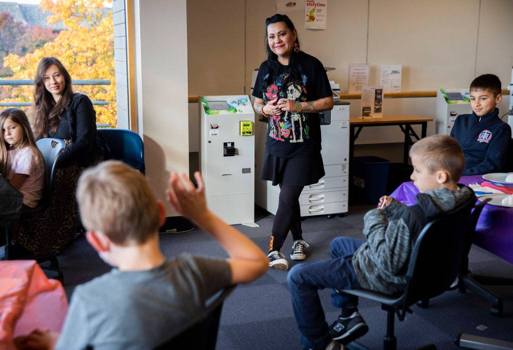 Artist Amaranta Ibarra-Sandys listens while a child explains what they think Dia de los Metros is during her sugar skull making workshop at the Edmonds Library on Tuesday, in Edmonds. (Olivia Vanni / The Herald)