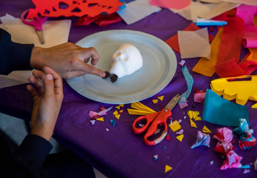 August Fisher, 9, places a bowtie on his sugar skull during a workshop at the Edmonds Library on Tuesday, in Edmonds. (Olivia Vanni / The Herald)