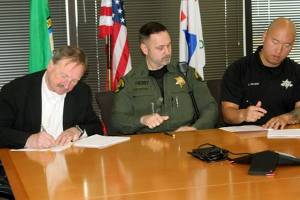 Snohomish County Executive Dave Somers, left, Sheriff Adam Fortney and Deputy Sheriffs Association President Jonathan Krajcar sign a new contract between Snohomish County and the Deputy Sheriff's Association on Nov. 2, 2022. (Snohomish County)