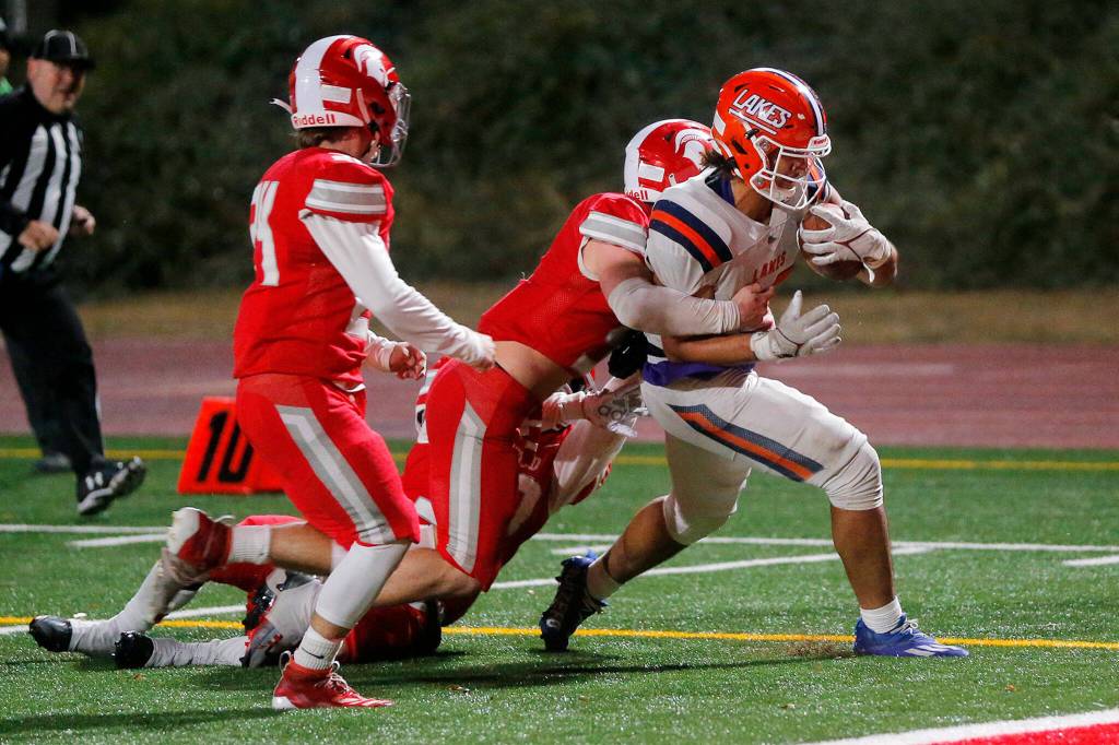Lakes High Schools Leo Pulalasi carries a defender into the end zone for a score against Stanwood on Friday, Nov. 4, 2022, at Stanwood High School in Stanwood, Washington. (Ryan Berry / The Herald)