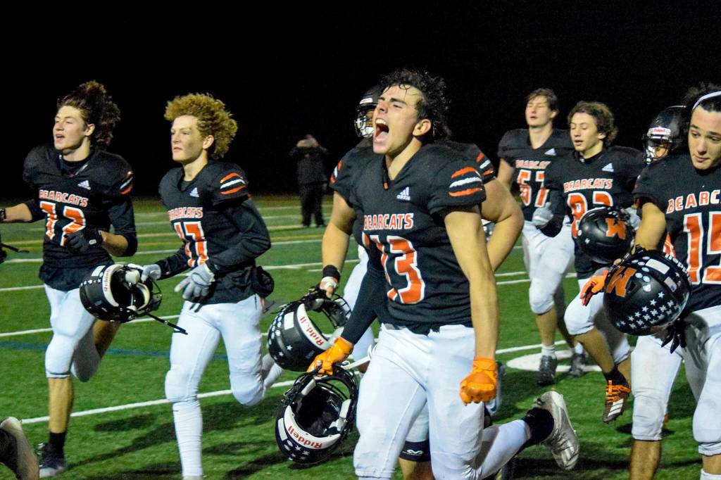 Monroe senior Eli Miller and his teammates run towards the stands after Monroes victory over Liberty on Friday, Nov. 4, 2022 in Monroe, Washington. (Katie Webber / The Herald)