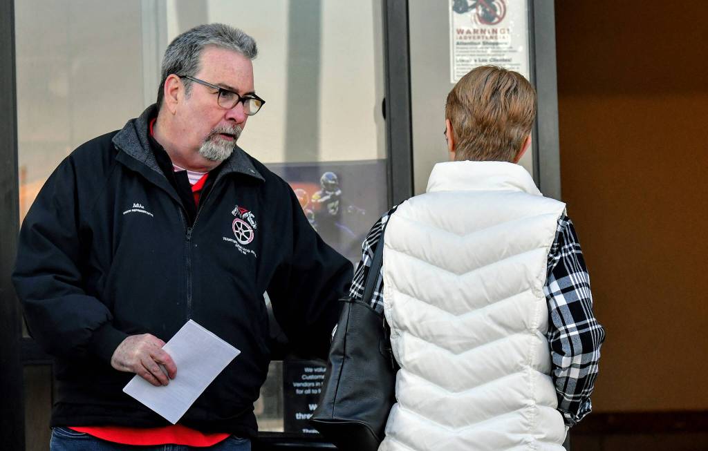 Mike Raughter, a union representative with the Marysville Albertsons, hands a leaflet to a shopper during an informational campaign on Wednesday, Nov. 9, 2022. Raughter was one of about a dozen grocery store workers handing out leaflets to shoppers about the proposed merger between Albertsons and Kroger. (Mike Henneke / The Herald)