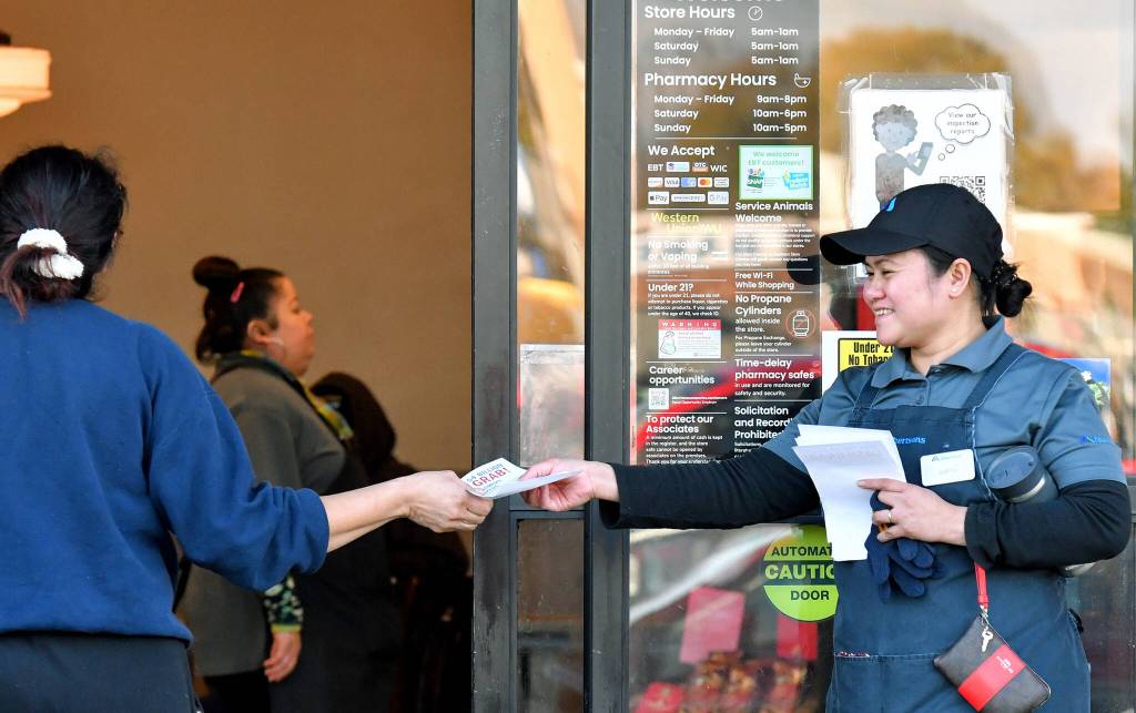 Joanne Fisher, right, a meat wrapper with the Marysville Albertsons, hands a leaflet to a shopper during an informational campaign on Wednesday, Nov. 9, 2022. Fisher was one of about a dozen grocery store workers handing out leaflets to shoppers about the proposed merger between Albertsons and Kroger. (Mike Henneke / The Herald)