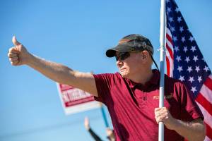State Representative Robert Sutherland, who is seeking re-election in the 39th District this year, gives a thumbs-up to passing drivers as he and a few volunteers wave flags and campaign signs along the side of State Route 9 on Friday, July 22, 2022, in Lake Stevens, Washington. (Ryan Berry / The Herald)