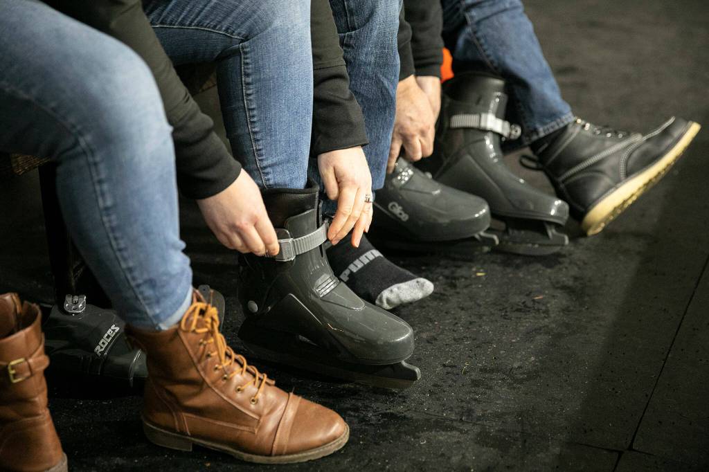 Kyria and Jason Brooks throw on their skates Friday before gliding on Arlingtons new seasonal ice rink at Legion Memorial Park. (Ryan Berry / The Herald)