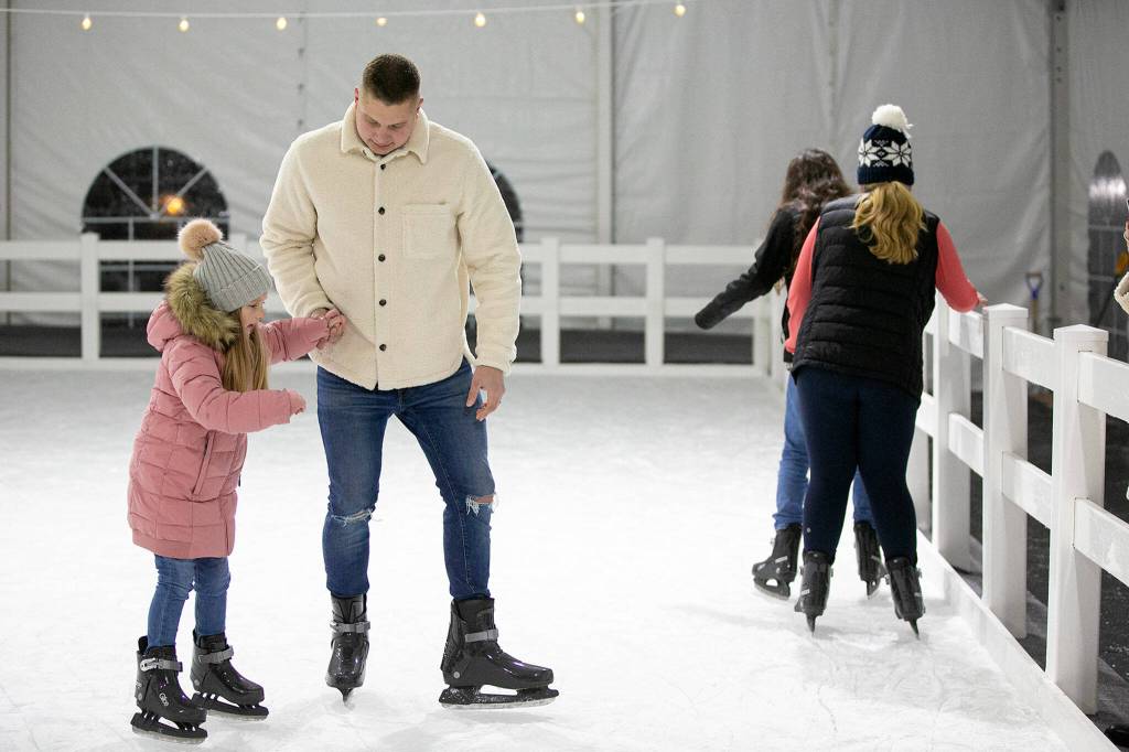 Dan Kurilchemko helps his daughter, Emzley, skate around on her sixth birthday Friday at Arlingtons new seasonal ice rink at Legion Memorial Park. (Ryan Berry / The Herald)