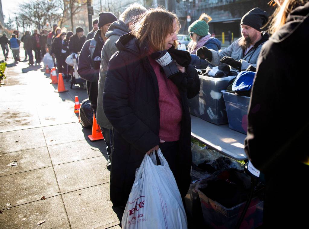 People line up to get gloves, hats and their choice of a sleeping bag or a ShelterSuit from Angel Resource Connection at the Carnegie Resource Center on Wednesday in Everett. (Olivia Vanni / The Herald)