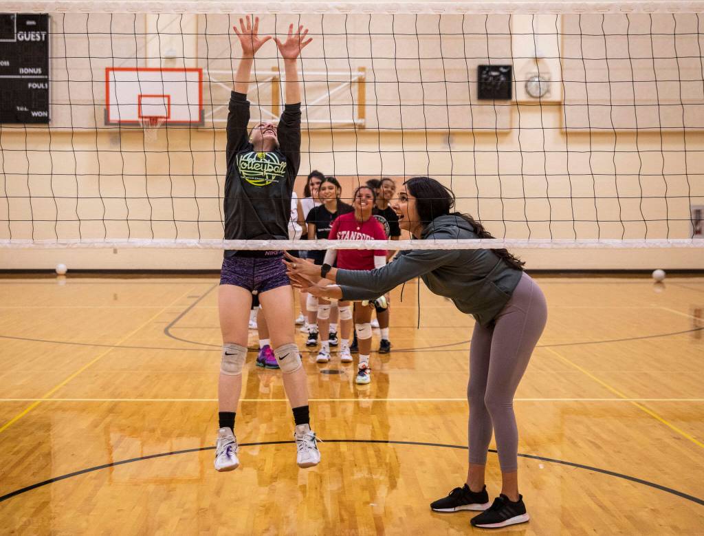 Coach Yuremi Lopez, right, yells words of encouragement while Cody Harmon, left tries to jump and reach above the net during a drill on Tuesday, Nov. 15, 2022 in Bothell, Washington. (Olivia Vanni / The Herald)